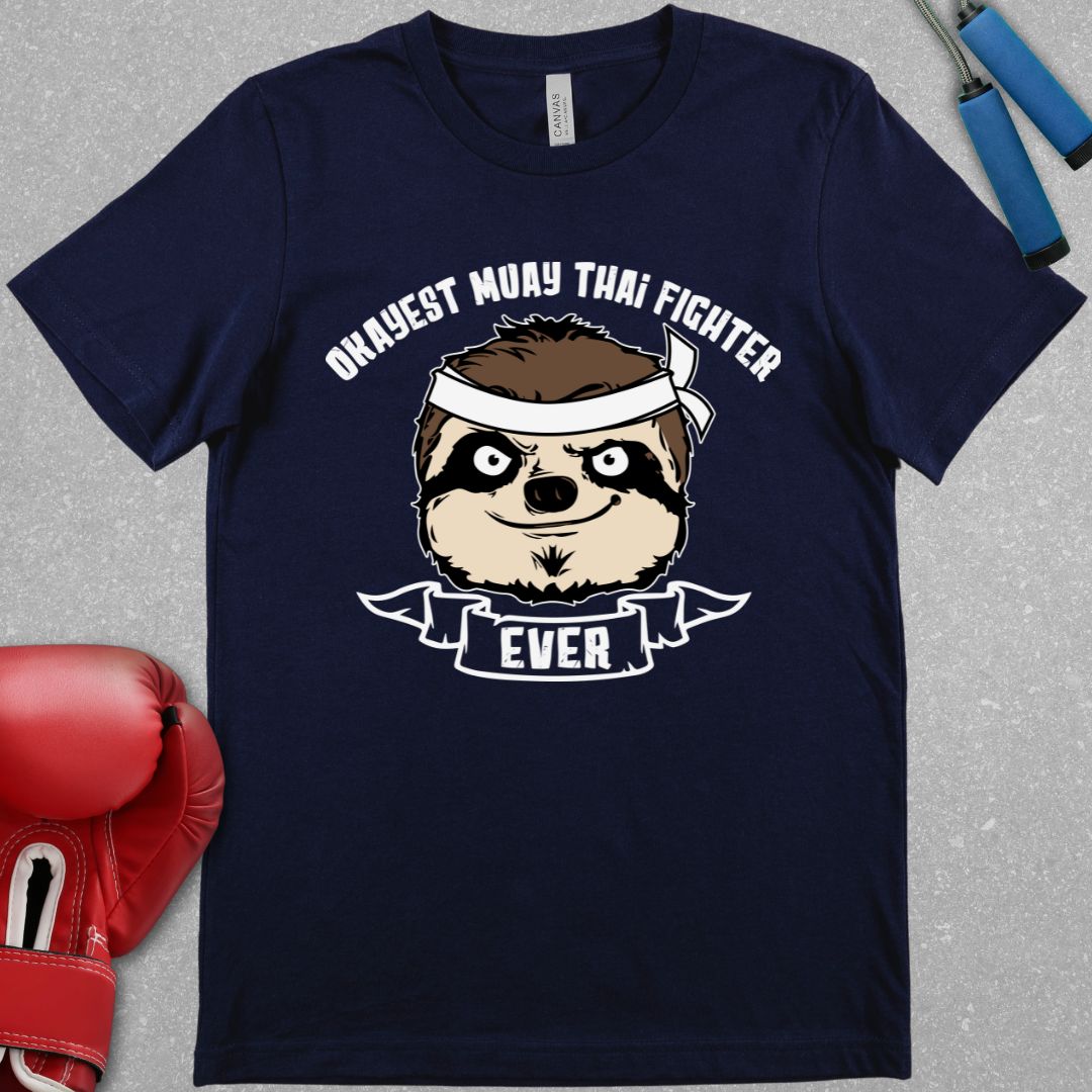 Navy shirt with text that says Okayest Muay Thai Fighter ever and there is  picture of a racoon’s face wearing a bandana